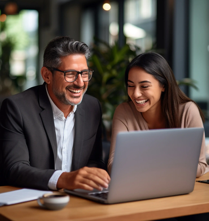 Two people working together on a laptop, both are laughing.